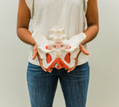 Femme tenant un os iliaque dans ses mains pour montrer que Shen Dao est une guidance basée sur le shiatsu du cycle menstruel